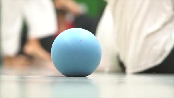 Der Ball rollt auf der Tanzfläche auf dem Hintergrund bewegter Füße. Impro-Tanz. — Stockvideo