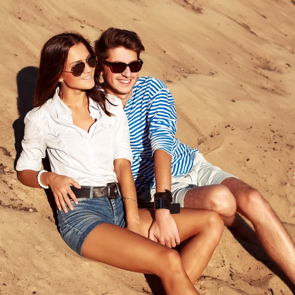 Молода пара моди сидить на пляжі — стокове фото
