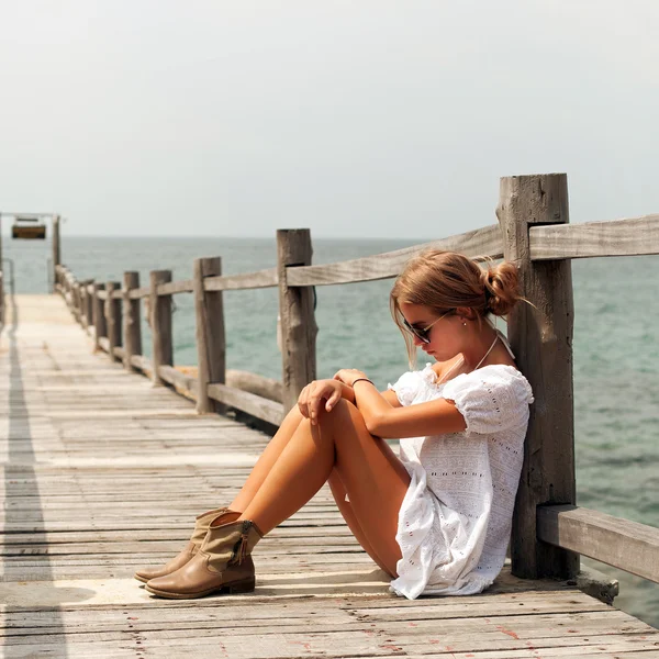 Woman in white dress sitting on the pier — Stock Photo, Image