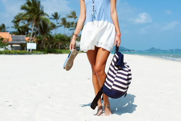 Vrouw aan het strand tonen gebruinde benen — Stockfoto