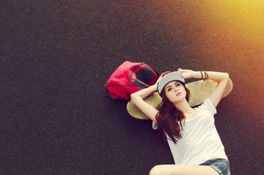 woman  lying on the ground with skateboard and backpack