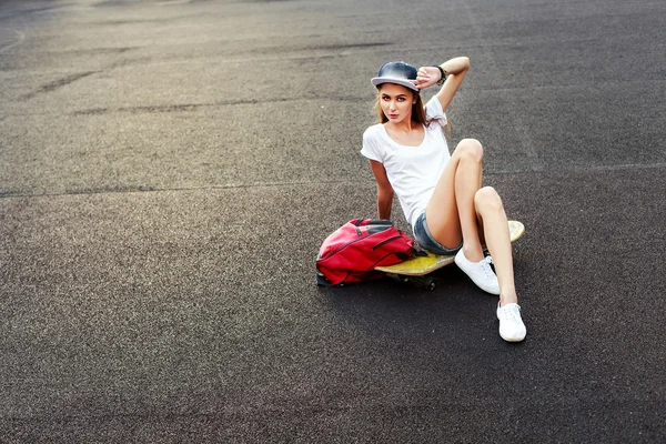 Девушка позирует на открытом воздухе со скейтбордом и рюкзаком — стоковое фото