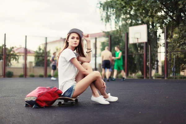 Chica posando al aire libre con monopatín y mochila — Foto de Stock