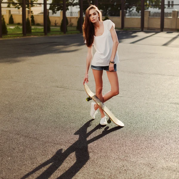 Девушка со скейтбордом на спортивном дворе школы — стоковое фото