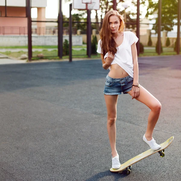 Woman with skateboard showing sexy body — Stockfoto