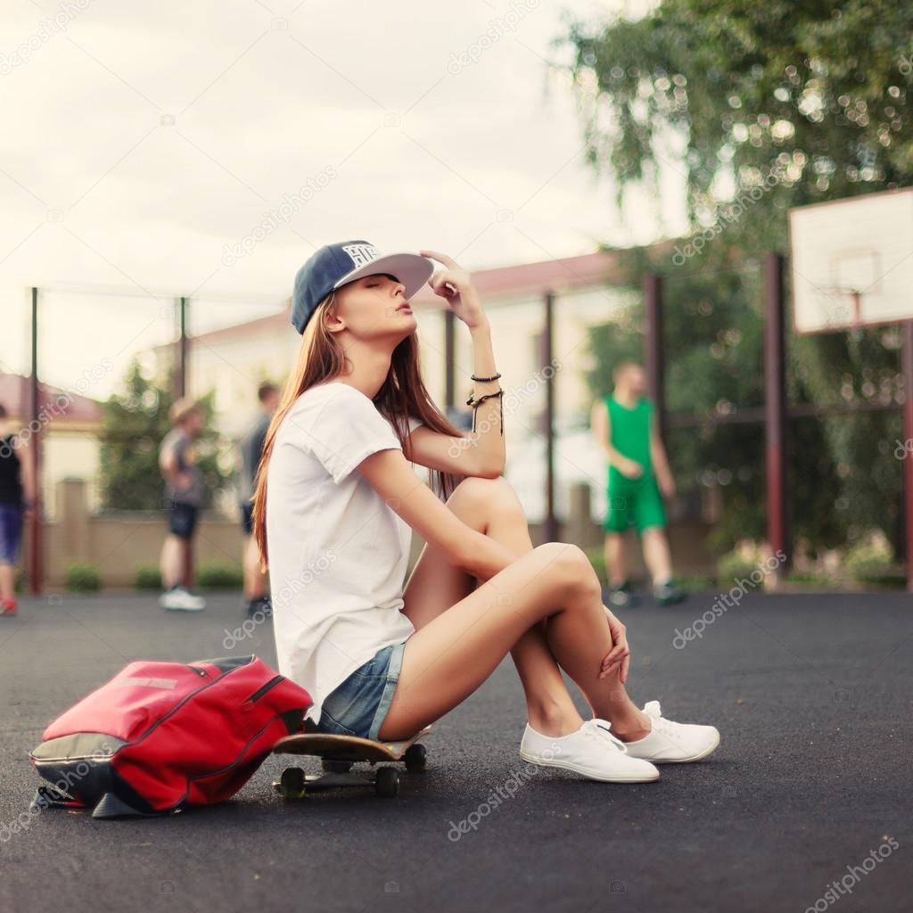 girl sitting on skateboard with backpack
