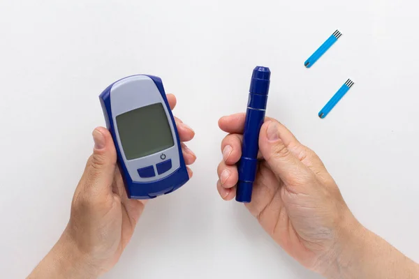 Top view of woman hands holding blood glucose meter and lancet on the white background — Stock Photo, Image