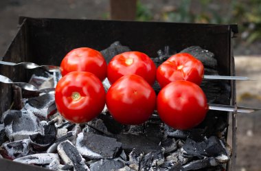 Barbeküde kızartılmış taze domatesler, kömürlü Ermeni Izgara Sebze Salatası khorovatları için malzeme olarak kullanılıyor.
