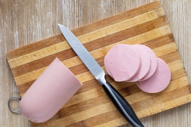 Tahta kesme tahtası ve bıçakla dilimlenmiş sosis manzarası