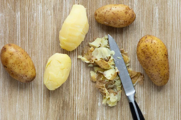 Top view of boiled potatoes in jackets and scrubbed on wooden background