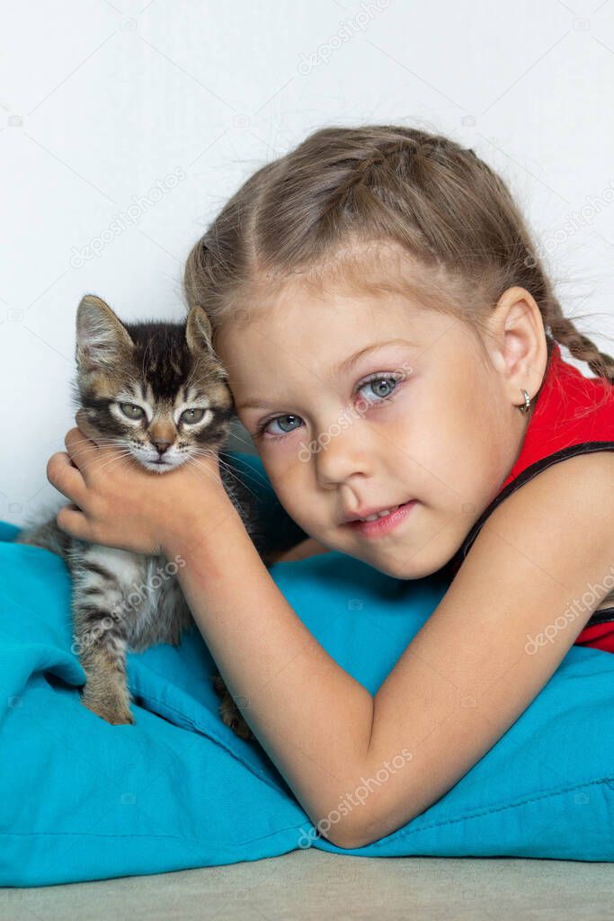 Portrait of cute caucasian girl of five years old holding kitten looking at camera on white background
