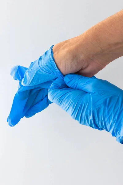 Visão superior das mãos da mulher colocando luvas azuis médicas no fundo branco — Fotografia de Stock