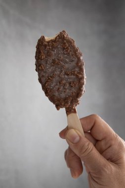 Bir kadının eli, çikolatalı buzlu çubukları biraz ısırır..