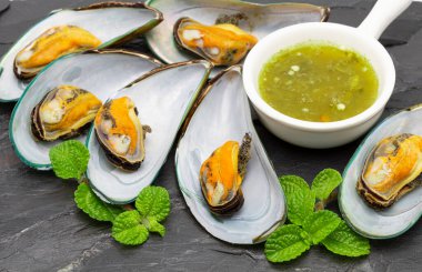 Baharatlı soslu midyeler siyah bir taşın üzerine konur..