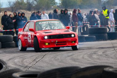 Buhovtsi, Bulgaristan - 12.10.2025 - Kalabalık yakından izlerken kırmızı bir araba bir yarış pistinde ustalıkla sürükleniyor. Olay serin bir sonbahar gününde, lastik dumanı yükselirken gerçekleşiyor..
