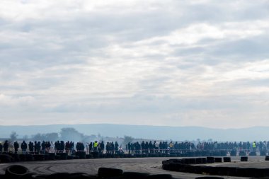 Bulgaristan 'ın Buhovtsi kenti - 12.10.2025 - büyük seyirci yarış pisti boyunca ayakta duruyor ve bir araba yarışının başlamasını sabırsızlıkla bekliyor. Sabahın erken saatlerinde bulutlar tepemizde sallanırken atmosfer heyecanla doludur..