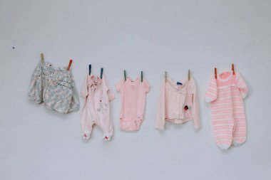 Duvarda asılı komik pembe yeni doğan elbiseler