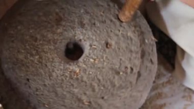 Buğday tohumlarını eski taş öğütücüsüne dolduran kızın yakın çekimi.