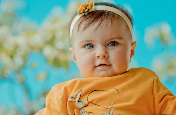一个彩色的图片可爱的婴儿与蓝色的眼睛和明亮的橙色衣服看着相机 — 图库照片