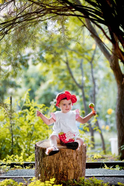 可爱的9个月大的婴儿 头顶着红色的弓 坐在树桩上微笑着 — 图库照片