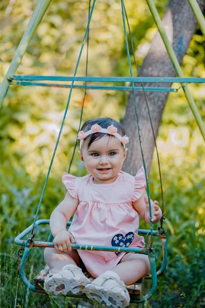在公园里 穿着紫色衣服坐在摇椅上的时尚小宝宝 — 图库照片