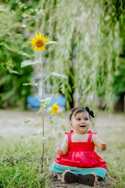 Szczęśliwy Dziewięciomiesięczne Dziecko Siedzi Ogrodzie Obok Słonecznika Uśmiecha — Zdjęcie stockowe