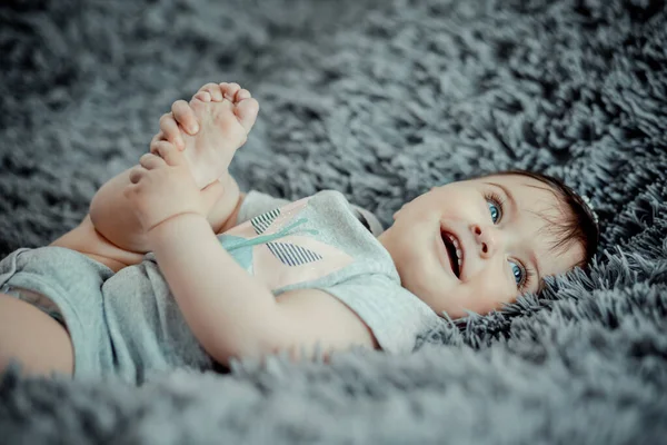 Neşeli Yedi Aylık Bebek Bacağını Tutuyor Gri Yumuşak Bir Çarşafın Telifsiz Stok Fotoğraflar