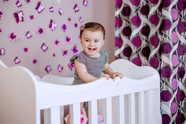 可爱可爱的婴儿在她的婴儿床里享受她的童年 有很多蝴蝶的漂亮的去神化卧室 — 图库照片