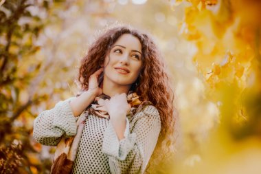 Gülümseyen kıvırcık saçlı kızın renkli sonbahar portresi 