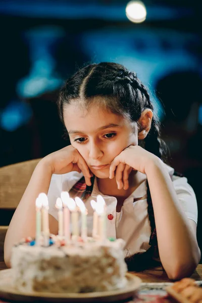 Sad girl looking at her birthday candles or making her birthday wish