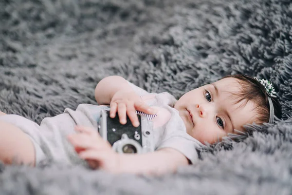 一个可爱的小宝宝的特写镜头 他拿着老式的刀片相机 躺在柔软的灰色床单上 — 图库照片