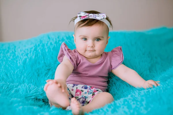 6个月大的婴儿 头上戴着创意彩带 坐在床上看着摄像机 — 图库照片