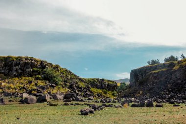 Mavi gökyüzü ve bulutlar kayalık arazide alçak açıyla çekilmiş.