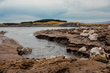 Baharda kara bulutlarla gölün kayalık kıyılarının alçak açılı görüntüsü