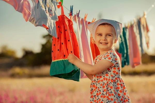 一个快乐可爱的小宝宝站在户外 穿着五颜六色的衣服 站在挂在绳子上的衣服旁边 — 图库照片