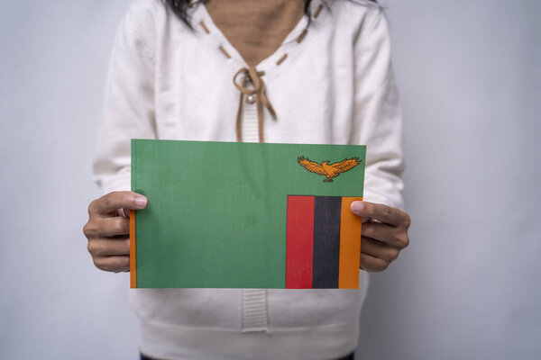 Person Holding Zambia National Flag Against Neutral Background