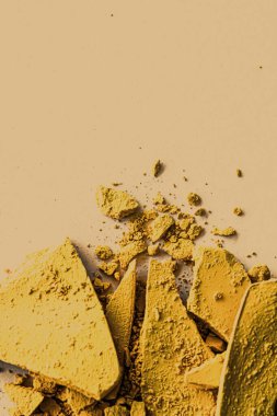 Makyaj paleti olarak sarı far pudrası, ezilmiş kozmetik ürünleri ve güzellik dokusu