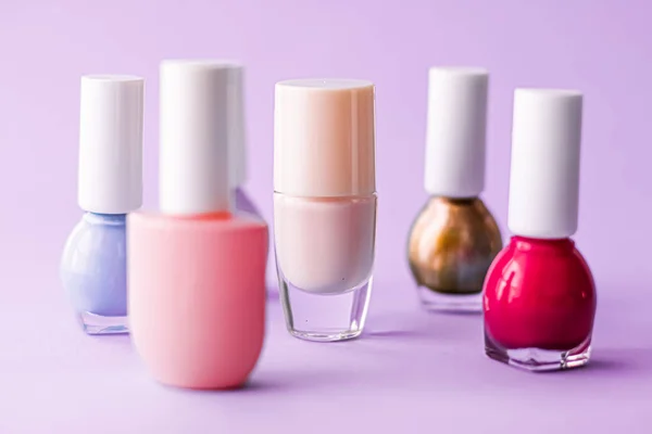 Nail polish bottles on purple background, beauty brand