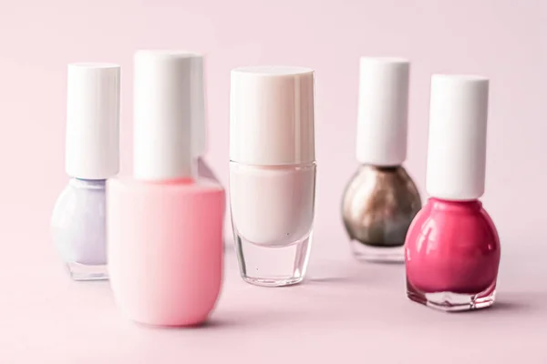 Nail polish bottles on blush pink background, beauty brand