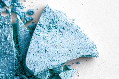 Makyaj paleti olarak mavi far pudrası beyaz arka planda izole edilmiş, ezilmiş kozmetik ve güzellik dokusu