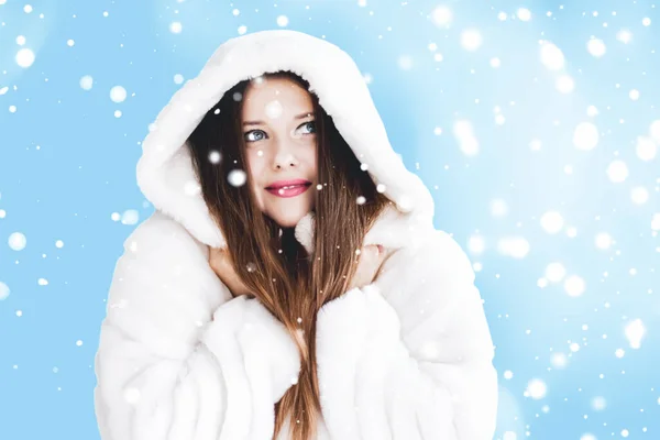 Weihnachts- und Winterurlaub Porträt einer jungen Frau in weißem Kapuzenpelzmantel, Schnee auf blauem Hintergrund, Mode und Lifestyle — Stockfoto