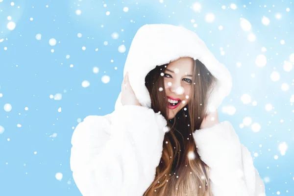 Natal e inverno férias retrato de jovem mulher de casaco de pele com capuz branco, neve no fundo azul, moda e estilo de vida — Fotografia de Stock