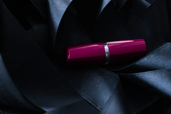 Lápiz labial púrpura sobre fondo de seda negro, maquillaje de lujo y cosméticos de belleza — Foto de Stock