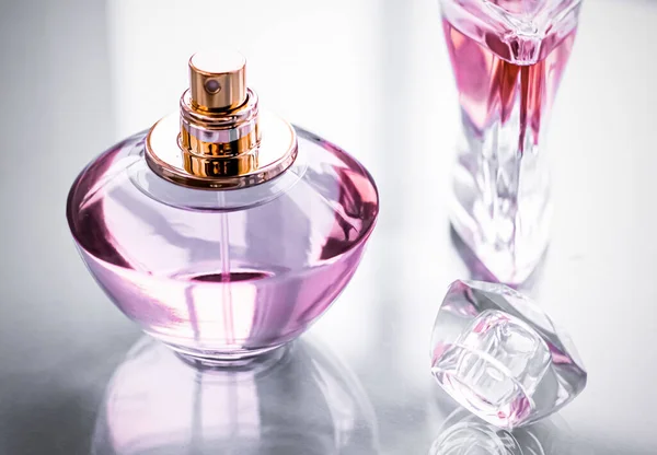 Μπουκαλάκι αρωμάτων ροζ σε γυαλιστερό φόντο, γλυκό λουλουδάτο άρωμα, λαμπερό άρωμα και eau de parfum ως δώρο διακοπών και πολυτελή καλλυντικά ομορφιάς brand design — Φωτογραφία Αρχείου