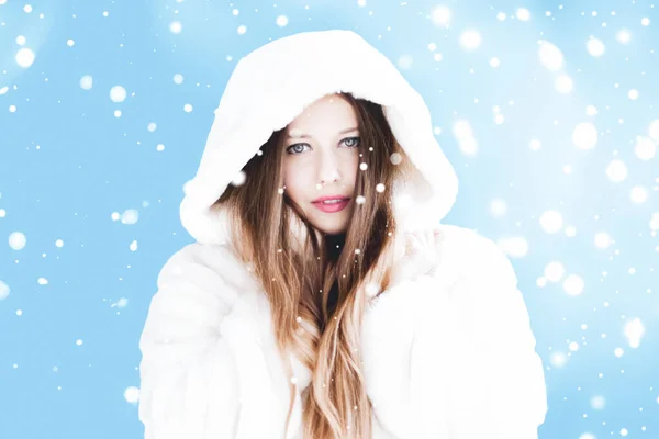 Świąteczne i zimowe wakacje portret młodej kobiety w białym płaszczu z kapturem, śnieg na niebieskim tle, moda i styl życia — Zdjęcie stockowe