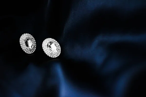 深蓝色丝质背景的豪华钻石耳环，节日华丽珠宝礼品 — 图库照片