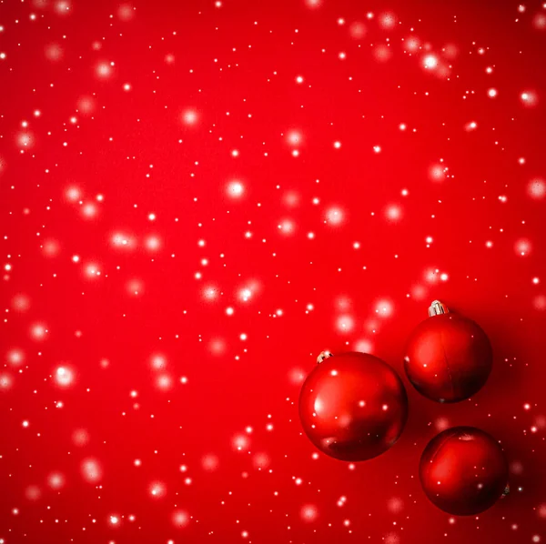 Рождественские безделушки на красном фоне с блестками от снега, роскошные зимние праздничные открытки — стоковое фото