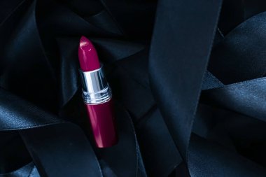 Siyah ipek arka planda mor ruj, lüks makyaj ve güzellik.