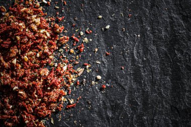 Kurutulmuş domates ve kırmızı biber, düz bir zemin, kuru yemek baharatları ve tarif malzemesi olarak lüks taş arka planda yakın plan