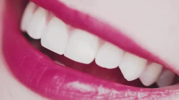 Dudakları pembe rujlu ve beyaz dişli gülümseyen, makro yakın plan mutlu kadın gülüşü, diş sağlığı ve güzellik makyajı — Stok video